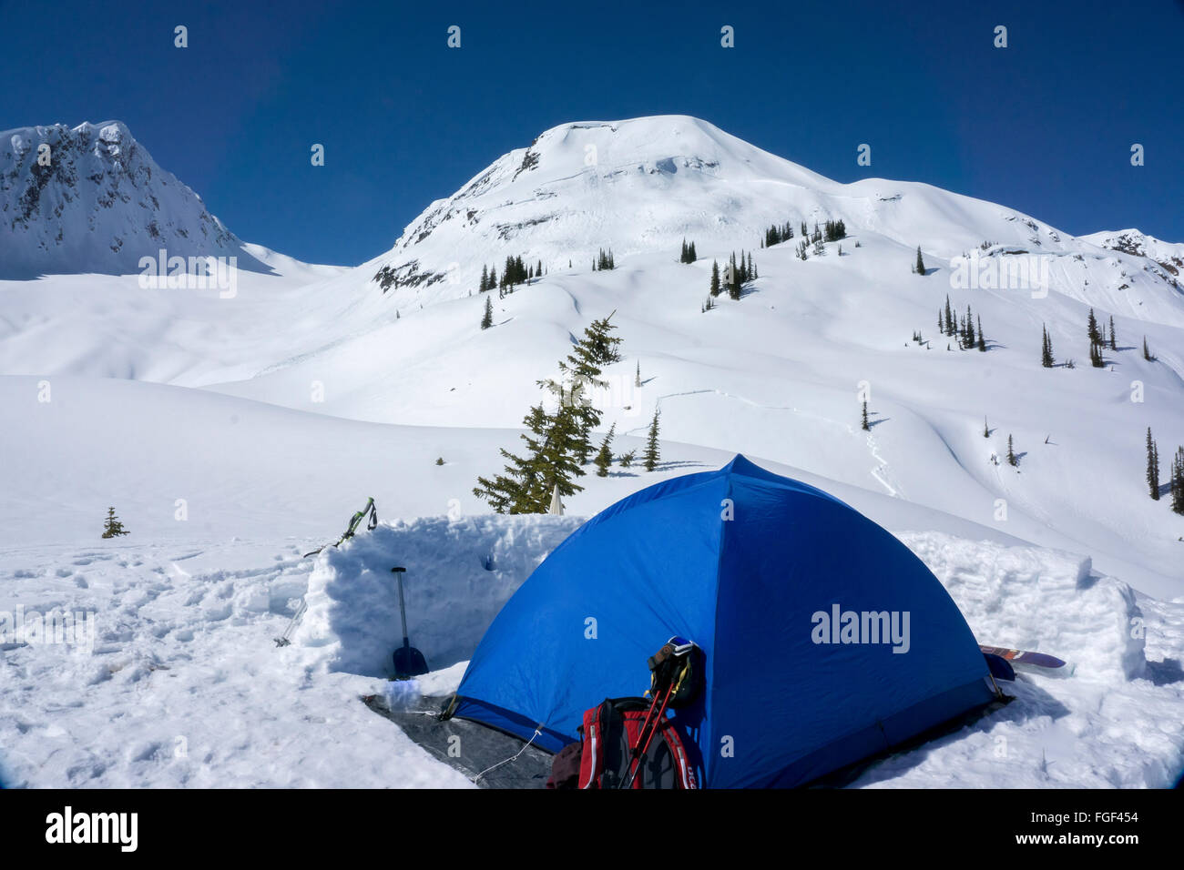 Eine blaue Zelt Zelte Backcountry Durg Wter British Columbia mit einer letzten Lawine auf der nahe gelegenen Hütte Stockfoto