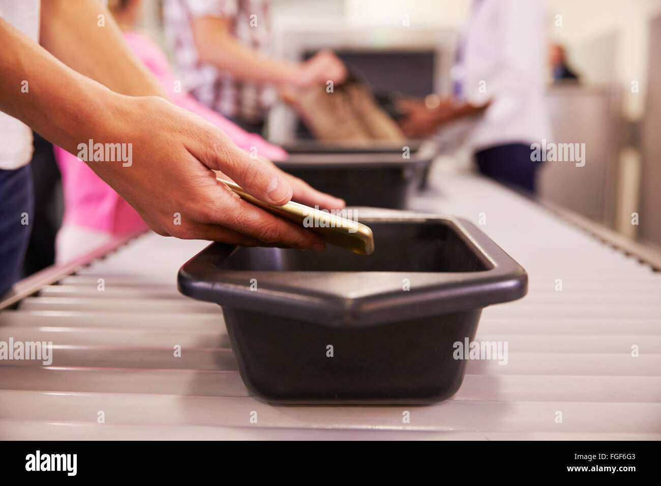 Mann stellt Handy in Fach für Flughafen-Sicherheits-Check Stockfoto