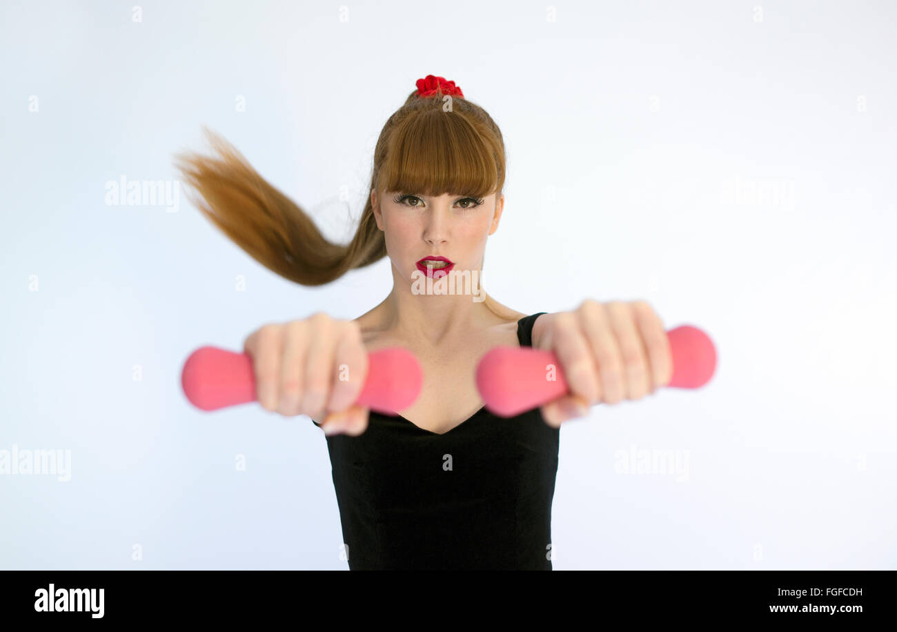 Frau mit langen braunen Haaren tragen eine Schweiß-Stirnband hält Rosa Hanteln trainieren Stockfoto