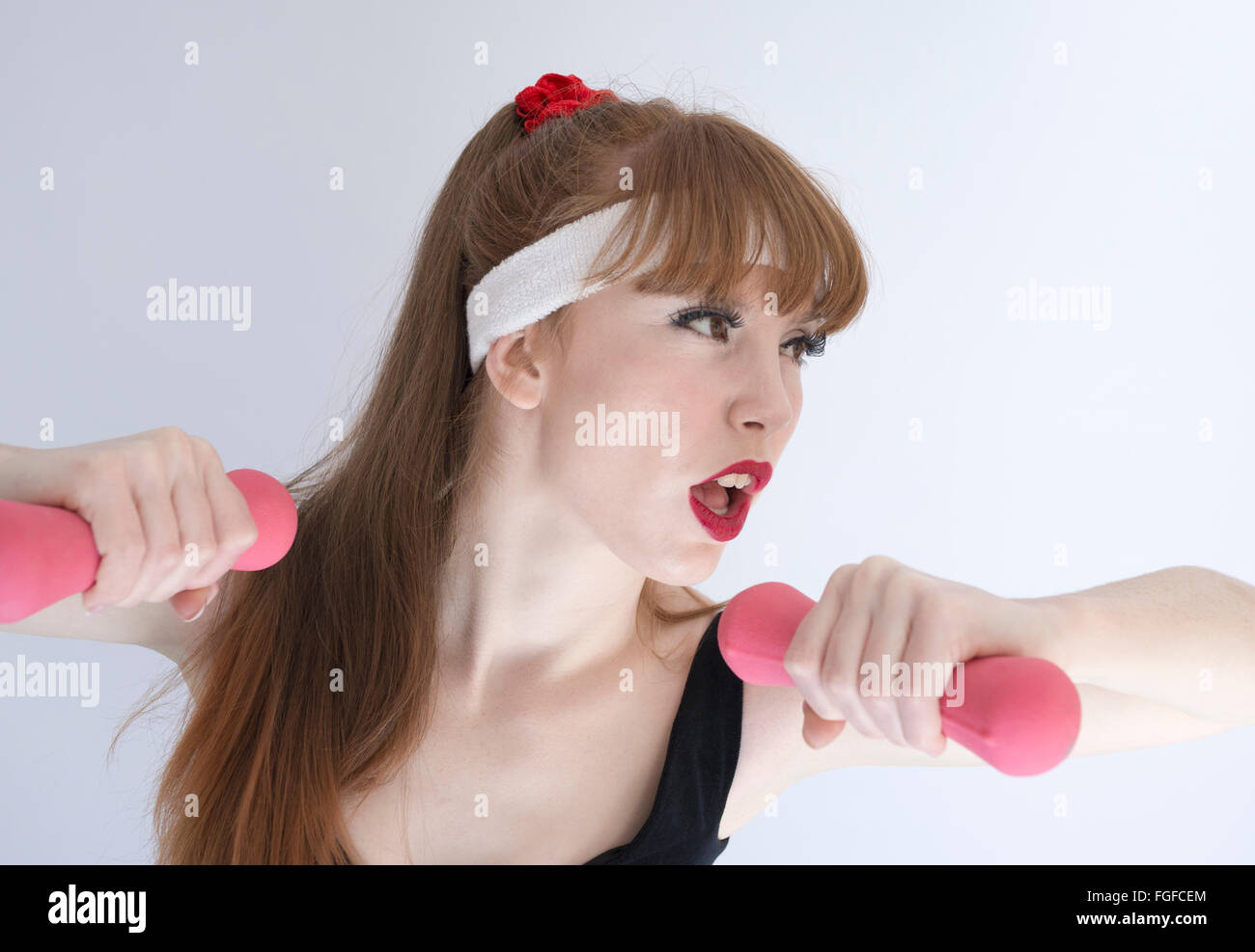Frau mit langen braunen Haaren tragen eine Schweiß-Stirnband hält Rosa Hanteln trainieren Stockfoto
