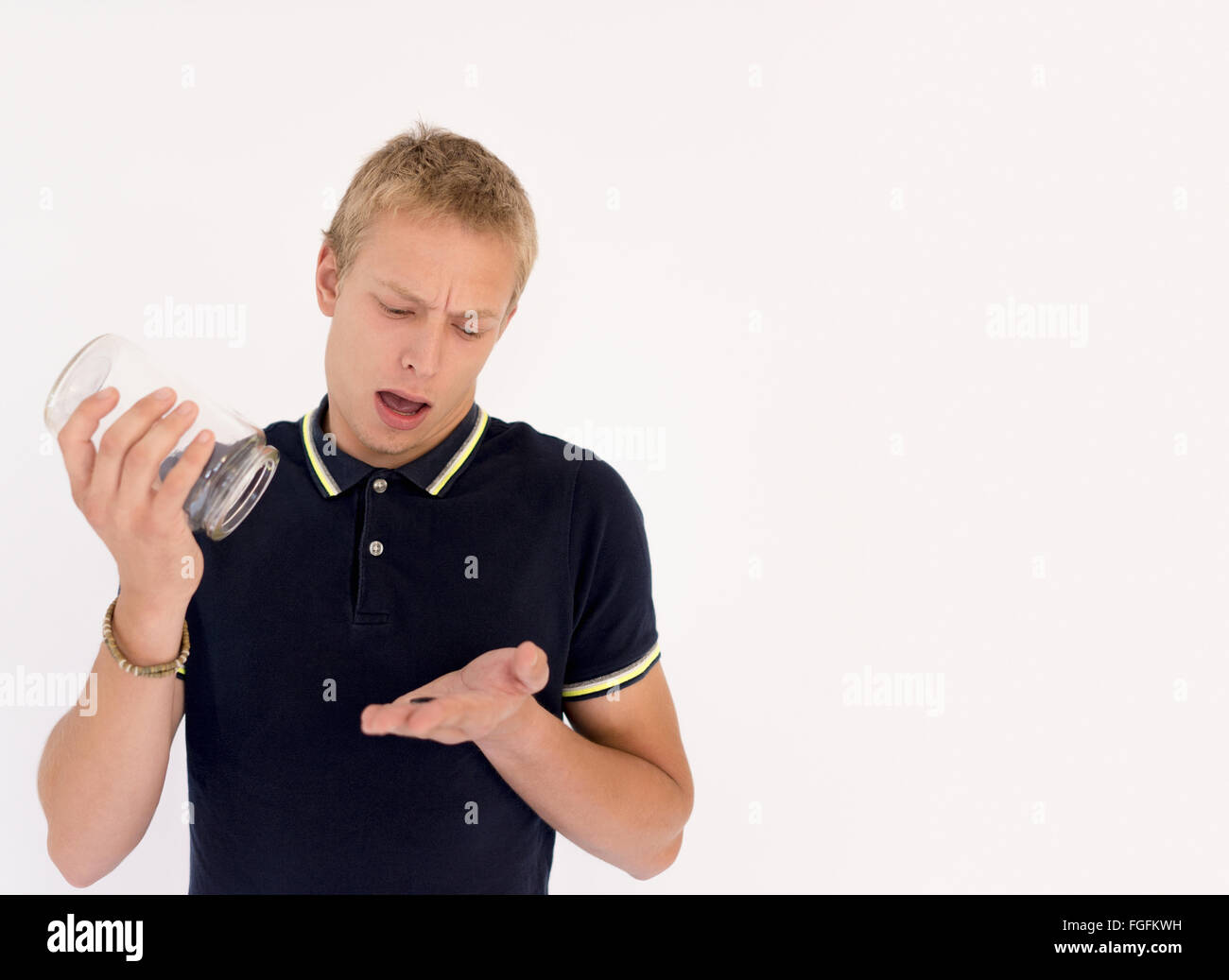 Mann ein Glas Geld entleeren nur zu finden, nur eine einzige Münze Stockfoto