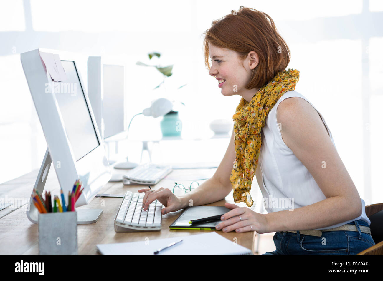 lächelnd Hipster-Business-Frau, die auf ihrem Computer eingeben Stockfoto