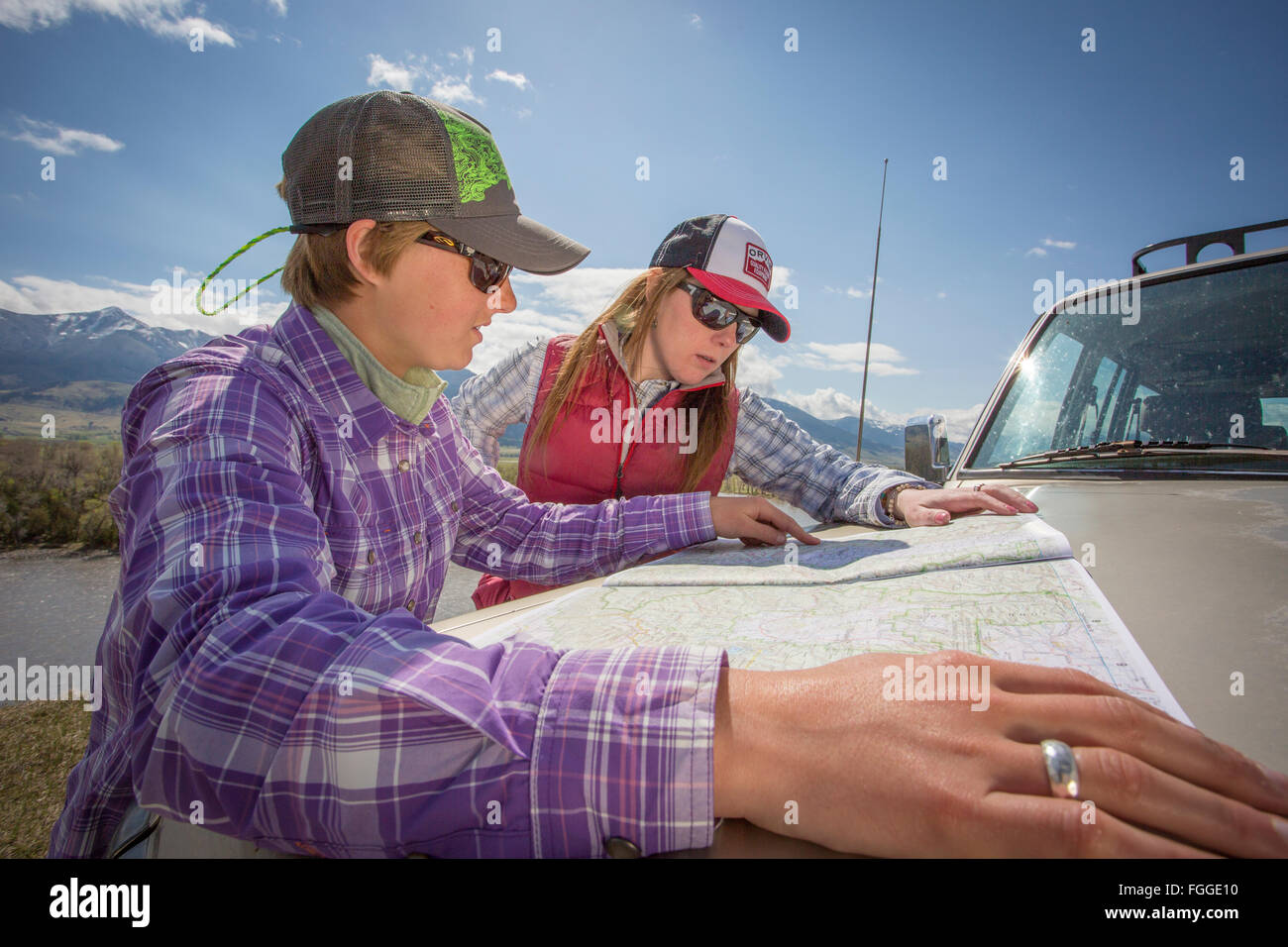 Frauen untersuchen Karten auf der Motorhaube ein 1900 Land Cruiser während der Fahrt über Yellowstone Land. Stockfoto