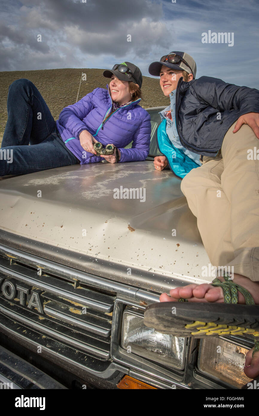 Zwei Frauen beobachten Wildtiere aus der Motorhaube ihres Autos während auf einem Roadtrip. Stockfoto