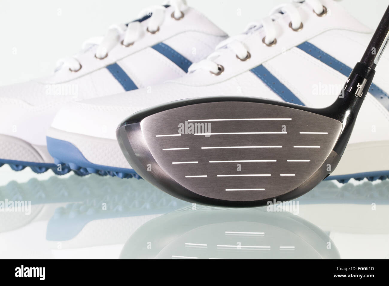 Golf Club und weiße Schuhe auf einem Glasschreibtisch Stockfoto