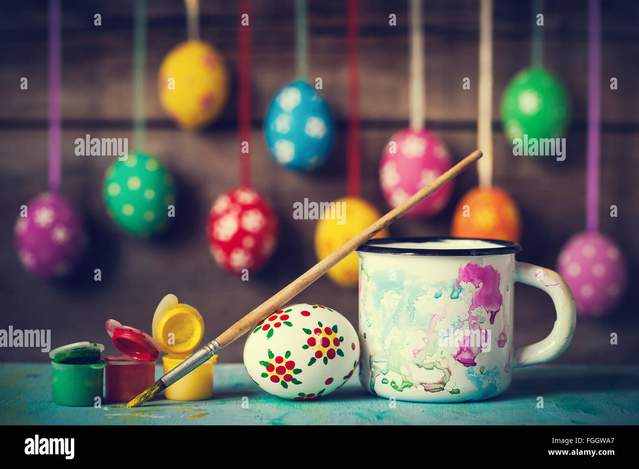 Malerei Ostereier und hängende bunte Eier auf rustikalen Holzmöbeln Hintergrund Stockfoto