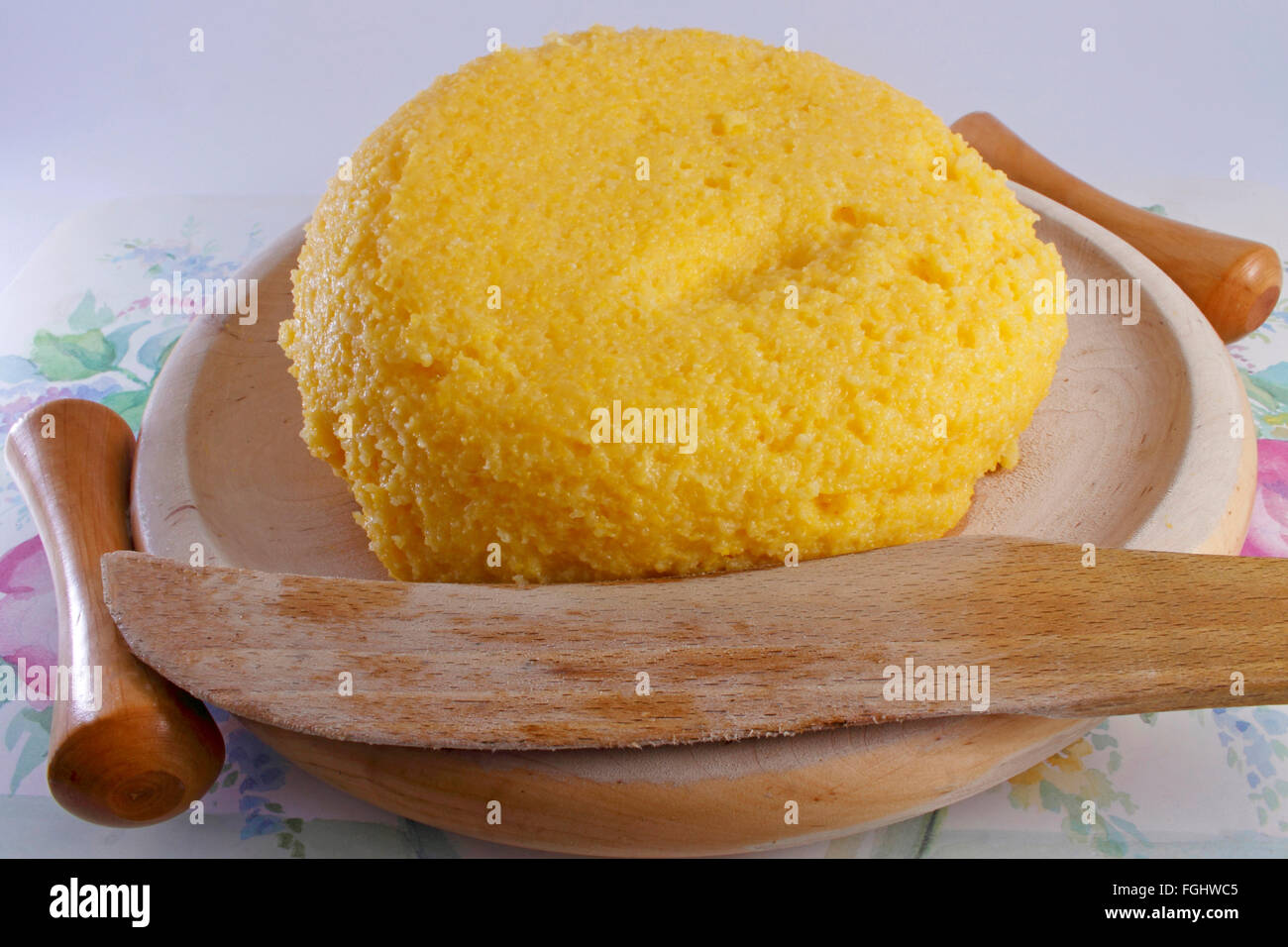 cremige Polenta mit einem hölzernen Messer auf eine hölzerne Untertasse Stockfoto