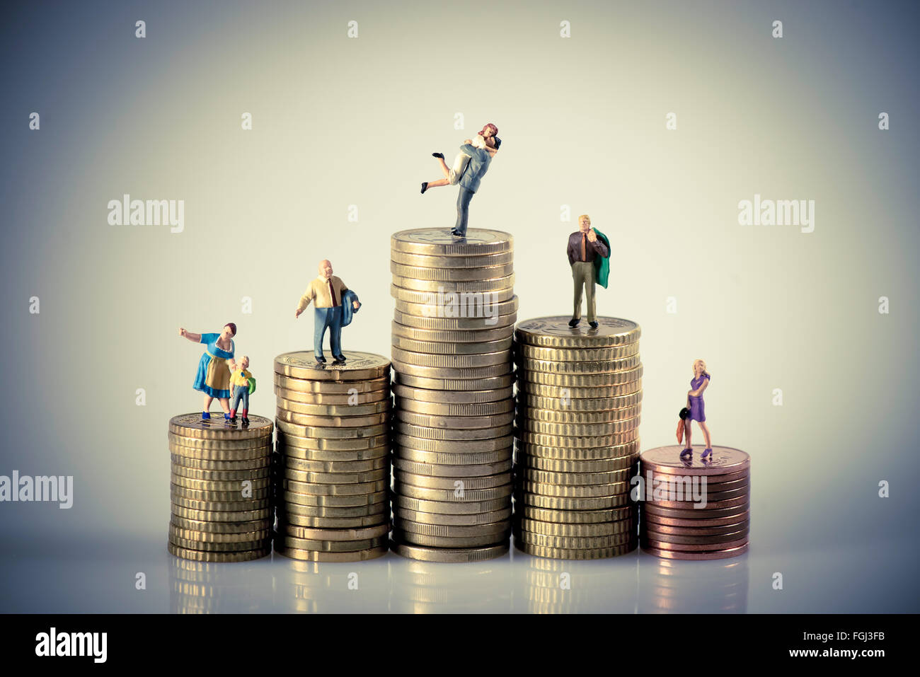 Wett-Budget-Konzept. Miniatur-Familie auf Münzen Haufen. Makro-Foto Stockfoto