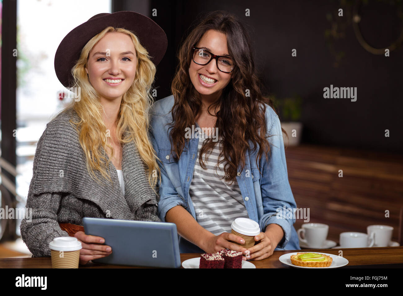 Lächelnd Freunde genießen Kaffee und Kuchen beim Tablet ansehen Stockfoto