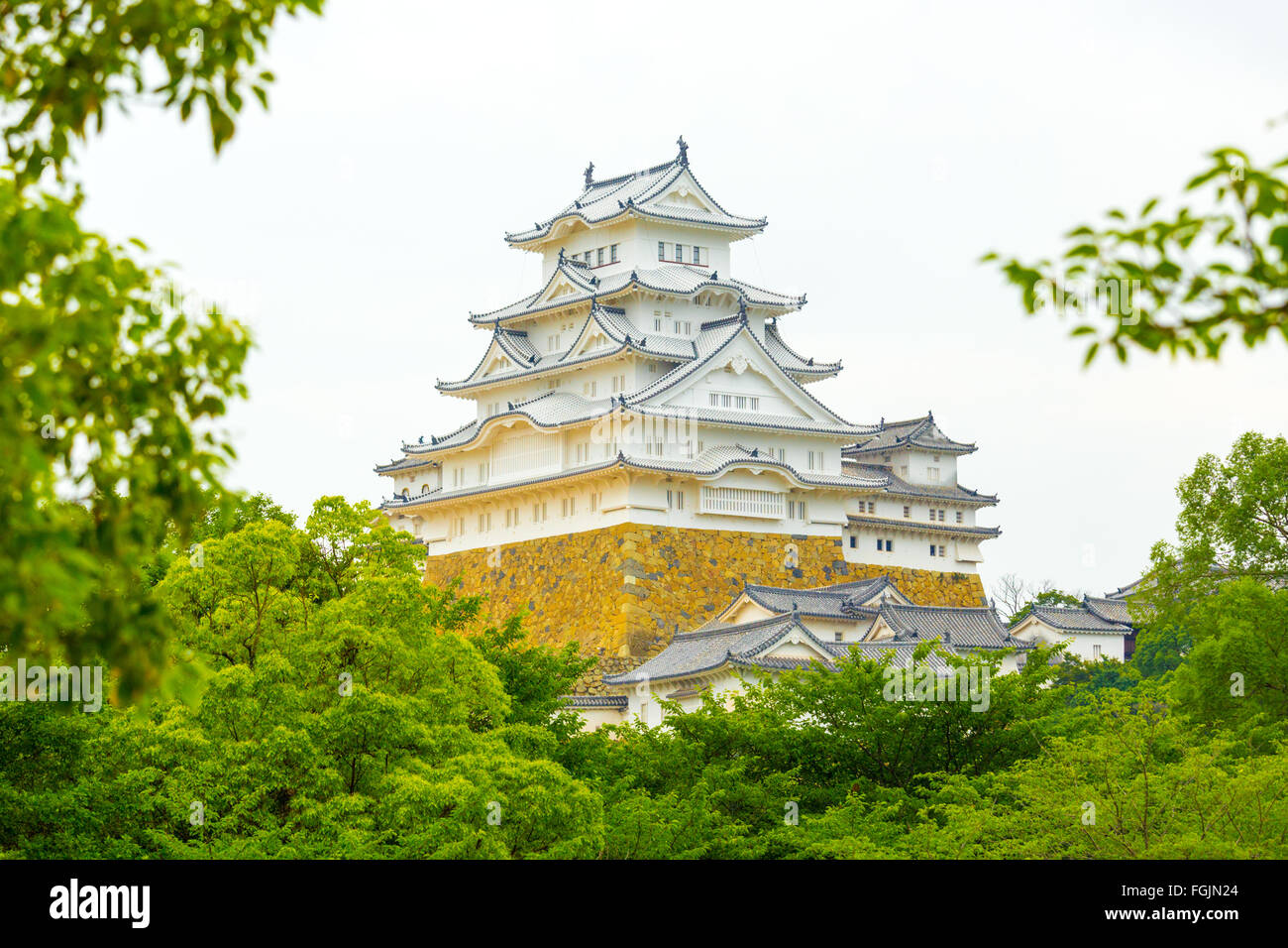 Bäume und Blätter umrahmen die schönen Details der Burg Himeji-Jo auf bedecktem Tag in Himeji, Japan nach 2015 Renovierungsarbeiten finis Stockfoto