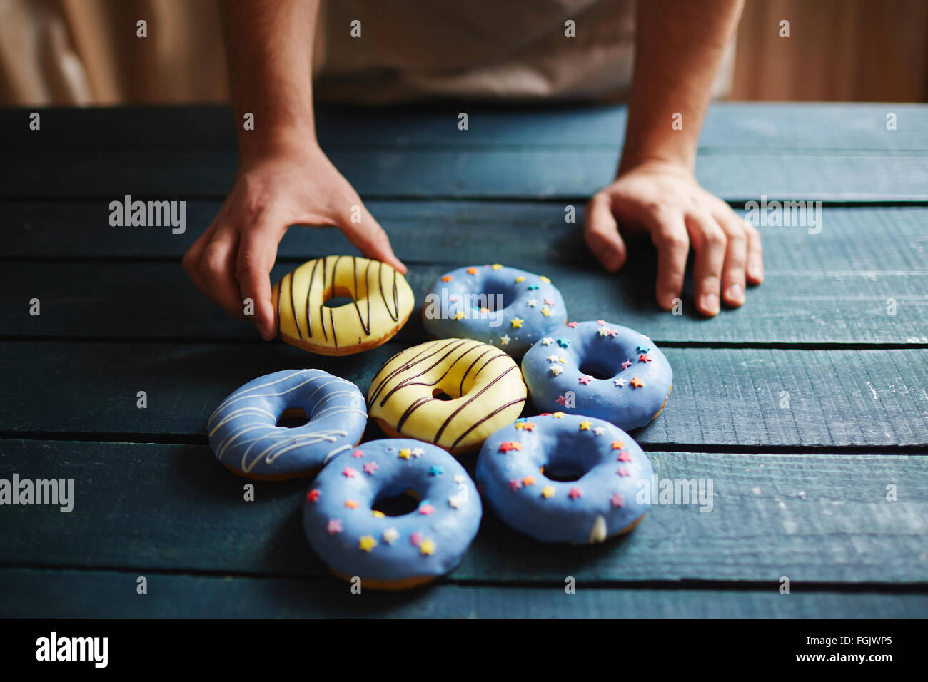 Baker, Donuts mit Zuckerguss auf Holztisch Stockfoto