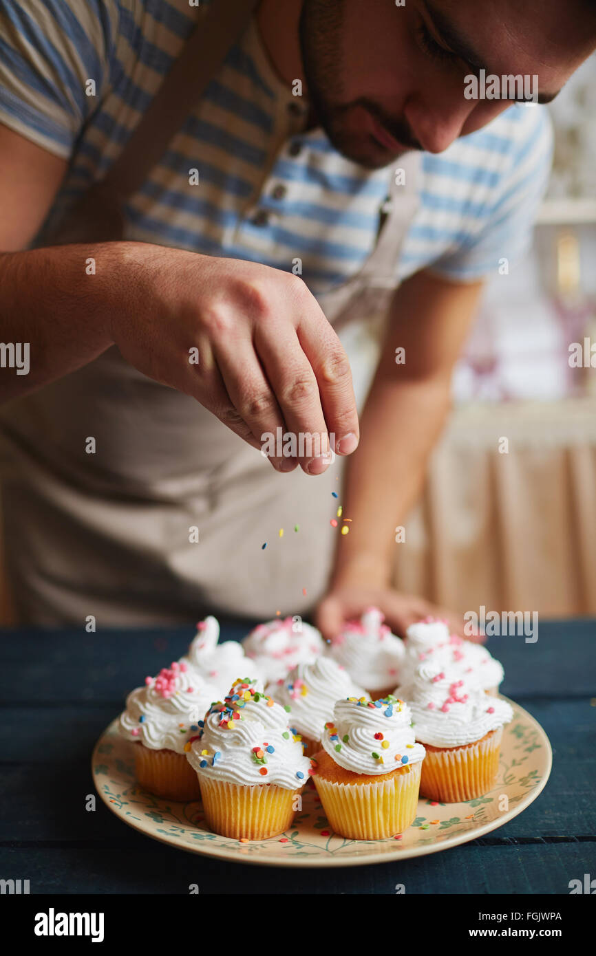 Baker, Muffins mit bunten Streuseln verzieren Stockfoto