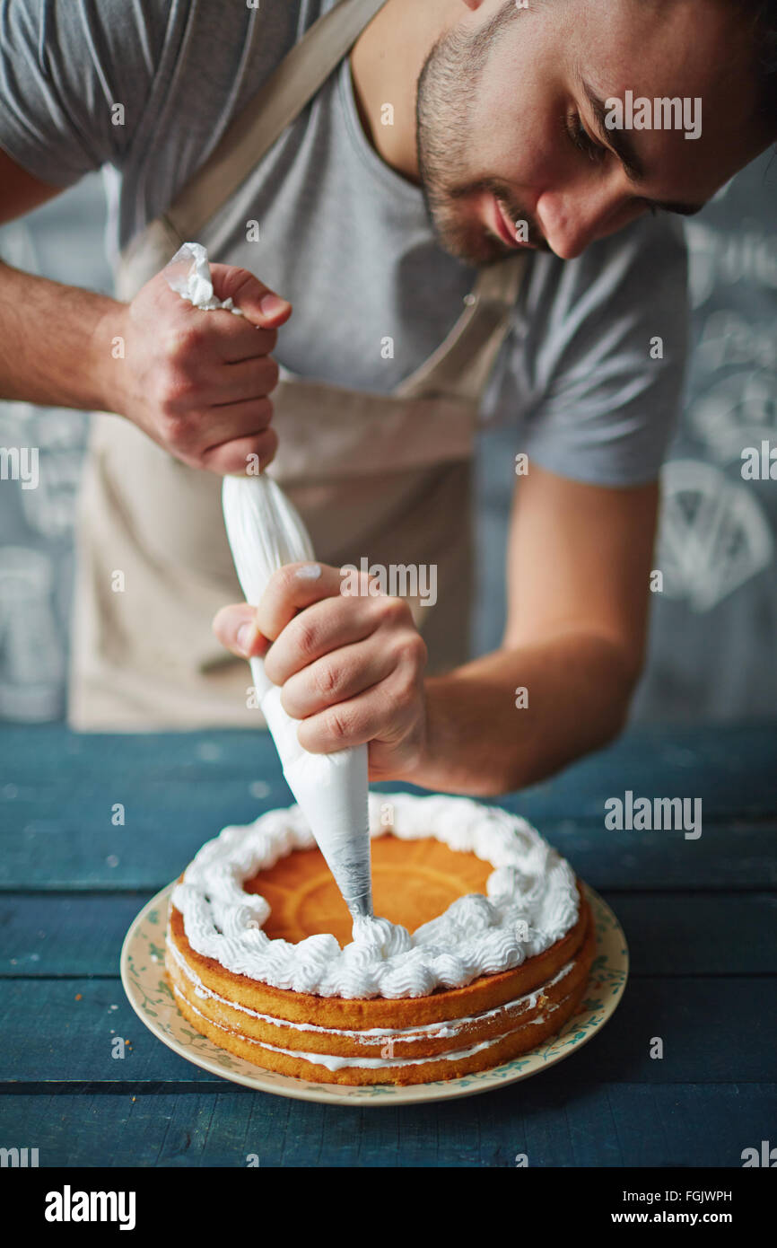 Baker, die leckeren Kuchen mit Schlagsahne verzieren Stockfoto
