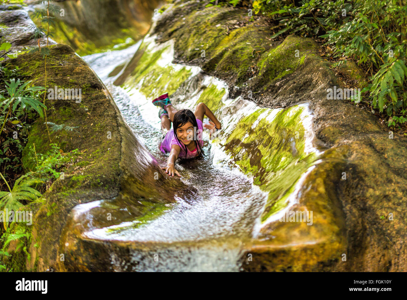 Kind auf Wasserrutsche im Wald, Lächeln und geniessen Stockfoto