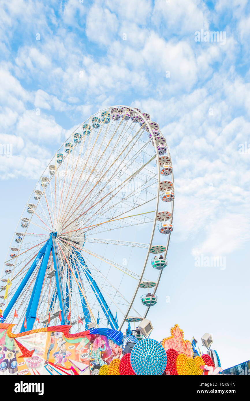 bunte Leuchtreklamen und Riesenrad auf Reisen Kirmes Stockfoto