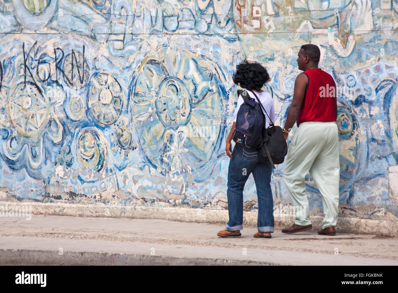 Kubanische paar vorbeigehen Wandbilder an Wand in Havanna, Kuba, Westindische Inseln, Karibik, Mittelamerika Stockfoto