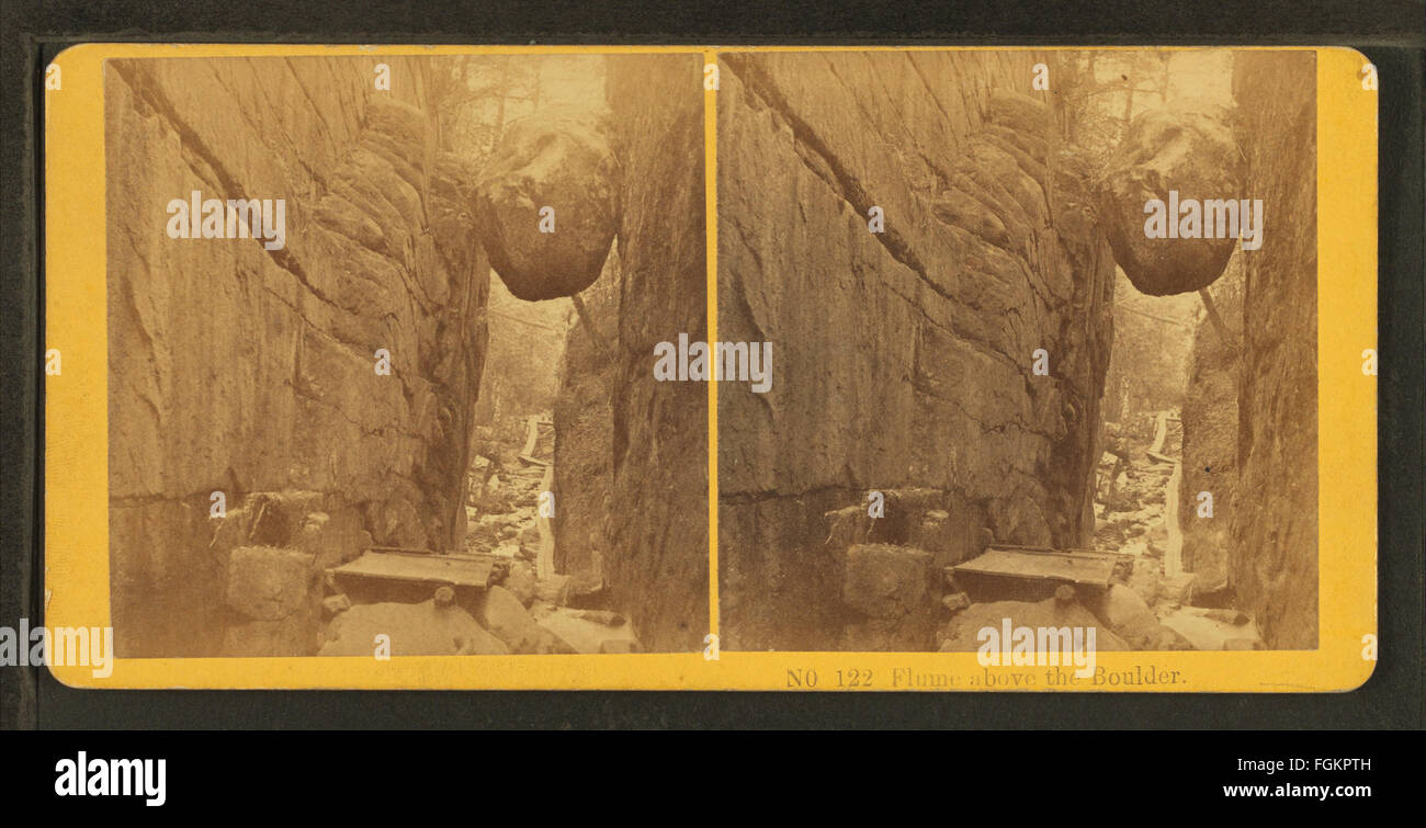 Dieses historische Foto mit dem Titel *Flume Above the Boulder* von Kilburn Brothers zeigt eine Szene aus dem 19. Jahrhundert und zeigt eine Wasserrinne, einen künstlichen Wasserkanal, der sich über einem Felsen in einer natürlichen Landschaft befindet. Das Bild hebt die technischen Wunder der damaligen Zeit hervor. Stockfoto