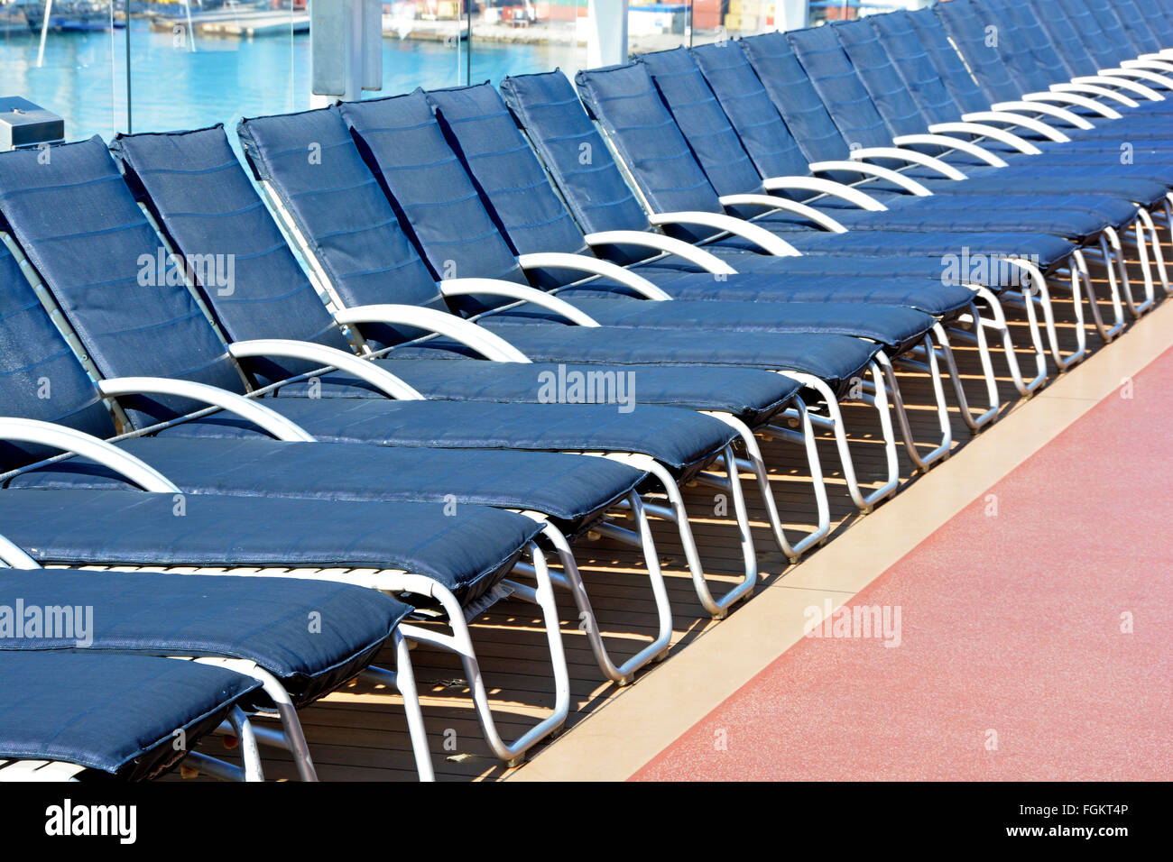 Kreuzfahrt Schiffsdeck am frühen Morgen Nahaufnahme der langen Reihe von leeren blauen Liegestühle warten auf Passagiere mit ihren Handtüchern zum Sonnenbaden Stockfoto