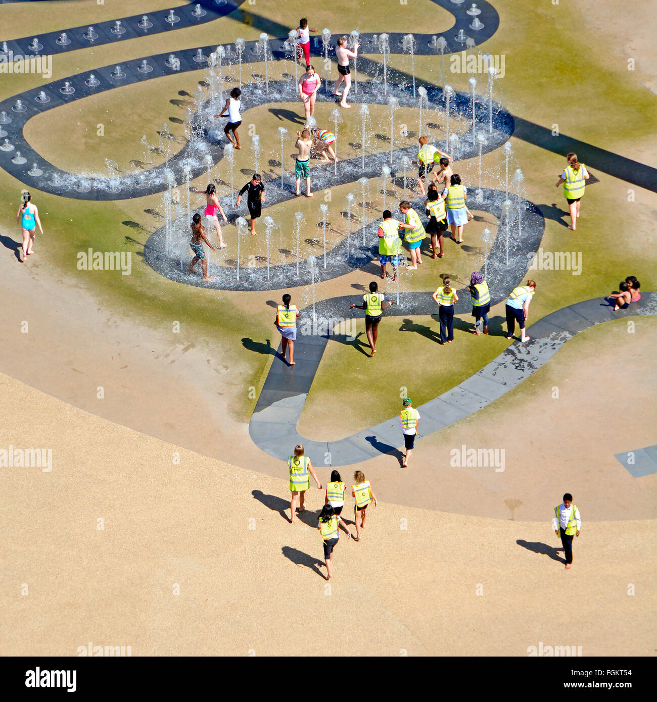 Luftaufnahme Kinder spielen draußen im Wasserbrunnen Jets Schulausflug heißer Sommer Queen Elizabeth Olympic Park London Newham Stratford East London UK Stockfoto