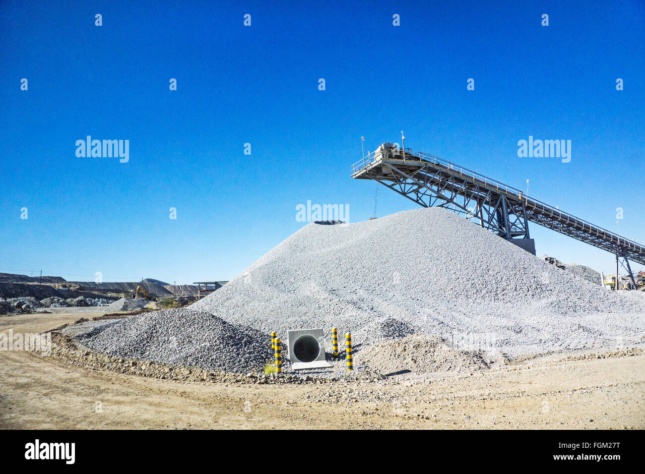 Förderband bewegt sich abgelehnten feinen Kies von Mühle, Pfähle warten auf Entfernung von Haul Truck Berme am Perimeter der Mission mir Stockfoto