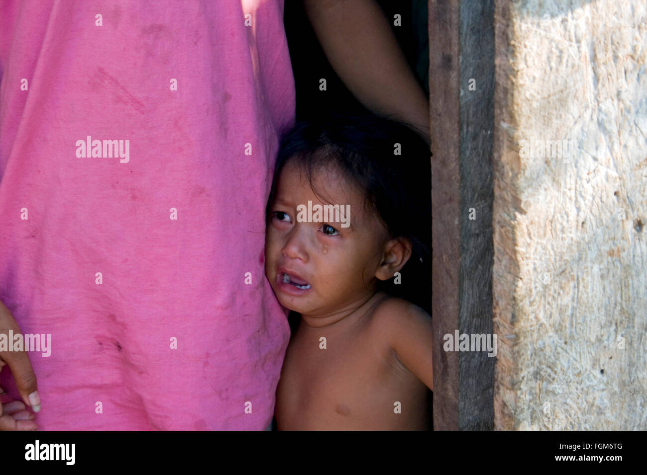 Ein junges Mädchen, die in Armut leben weint, da sie klammert sich an ihre Schwester in ihrem Holz Haus in Kampong Cham, Kambodscha. Stockfoto