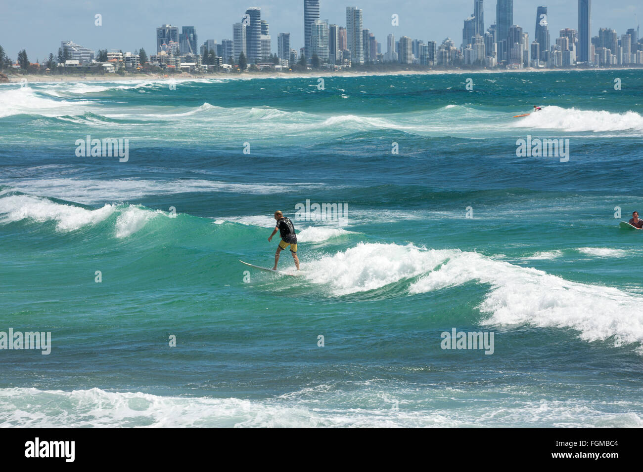 Menschen Surfen im Ozean in Burleigh Heads mit Surfers Paradise in der Ferne, Gold Coast, Queensland, Australien Stockfoto