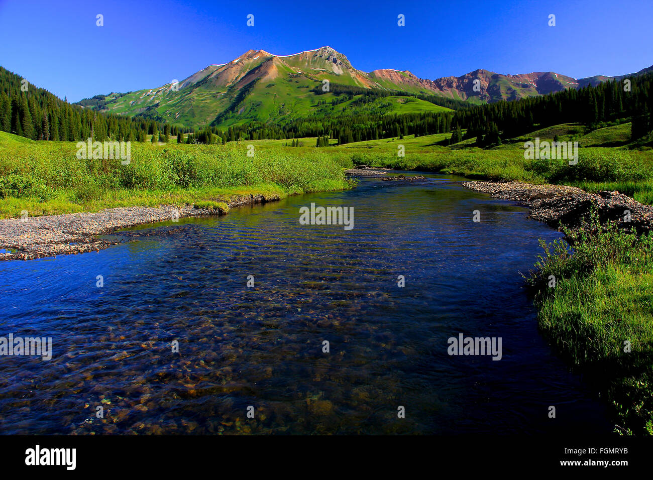 Colorado Rocky Mountains Ruby Range mit Fluss fließt durch die Wiese im Sommer in der Nähe von Crested Butte im Sommer Stockfoto