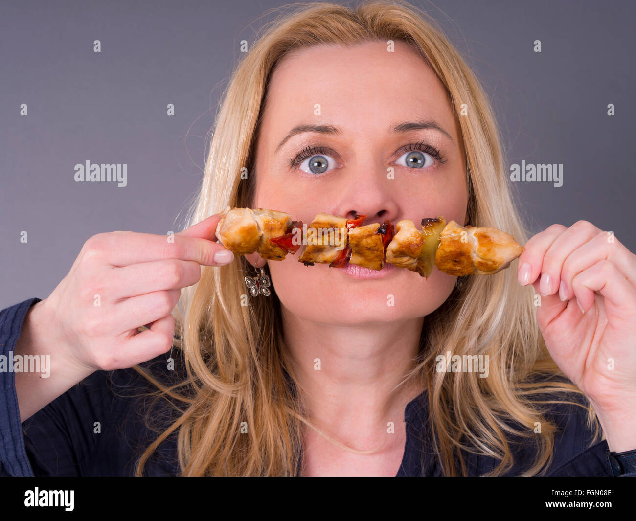 blonde Frau riechen gegrilltes Fleisch Stockfoto