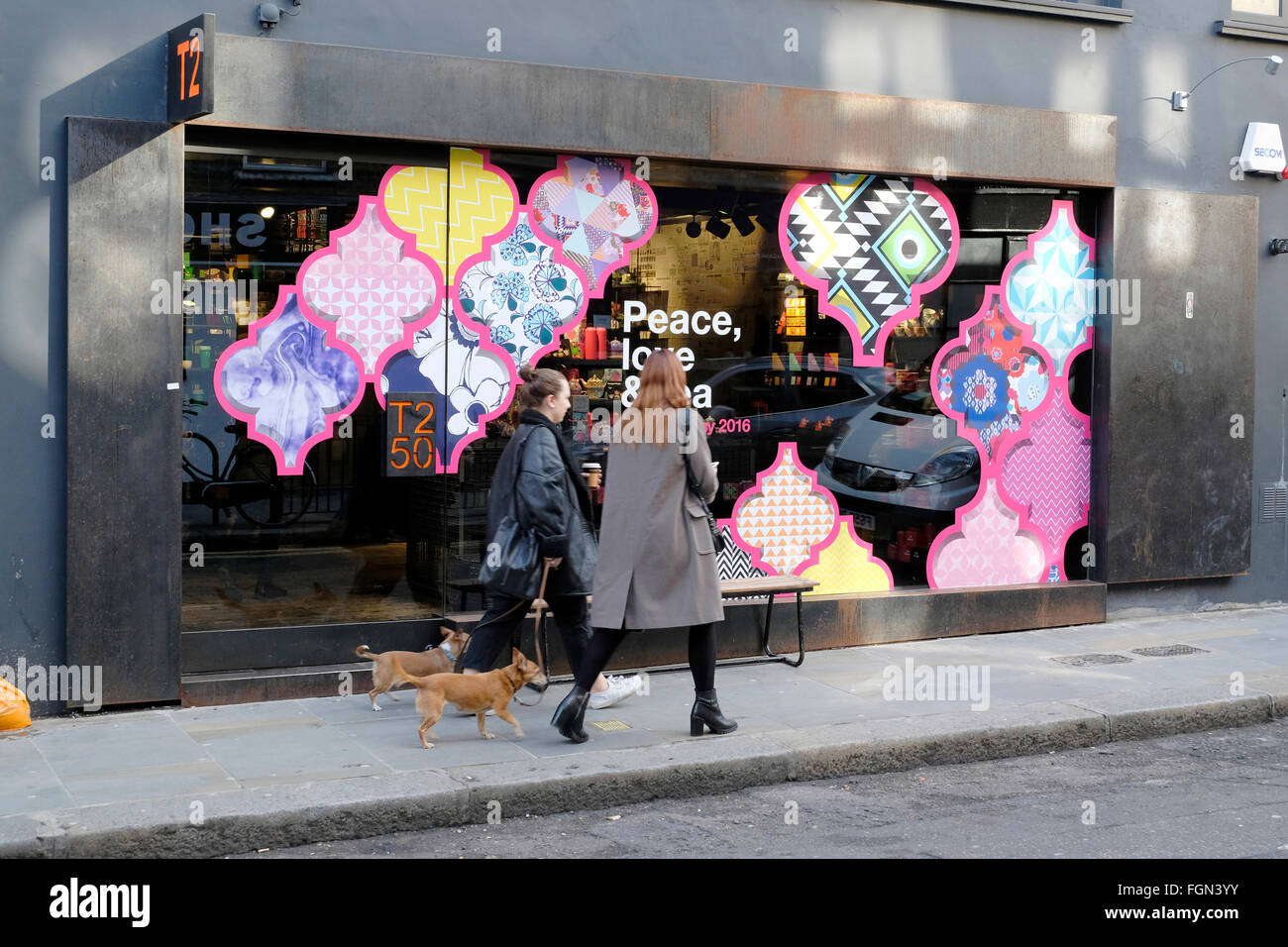 Zwei Frauen gehen mit Hunden vor einem farbenfrohen Geschäft Stockfoto