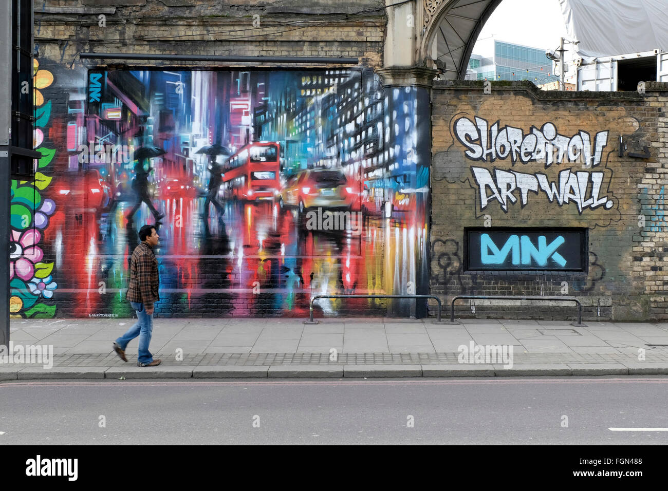 Ein Mann geht vorbei an einem Gemälde an der Wand in Shoreditch Stockfoto