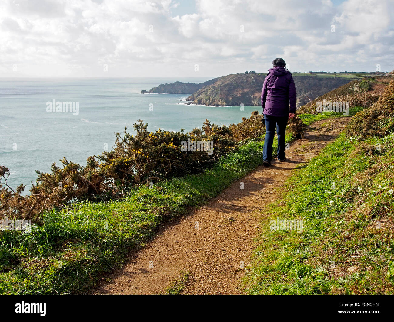 Walker auf dem Felsenweg oberhalb Le Jaonnet zwischen Icart Point und Le Petit Bot, Guernsey im zeitigen Frühjahr. Stockfoto