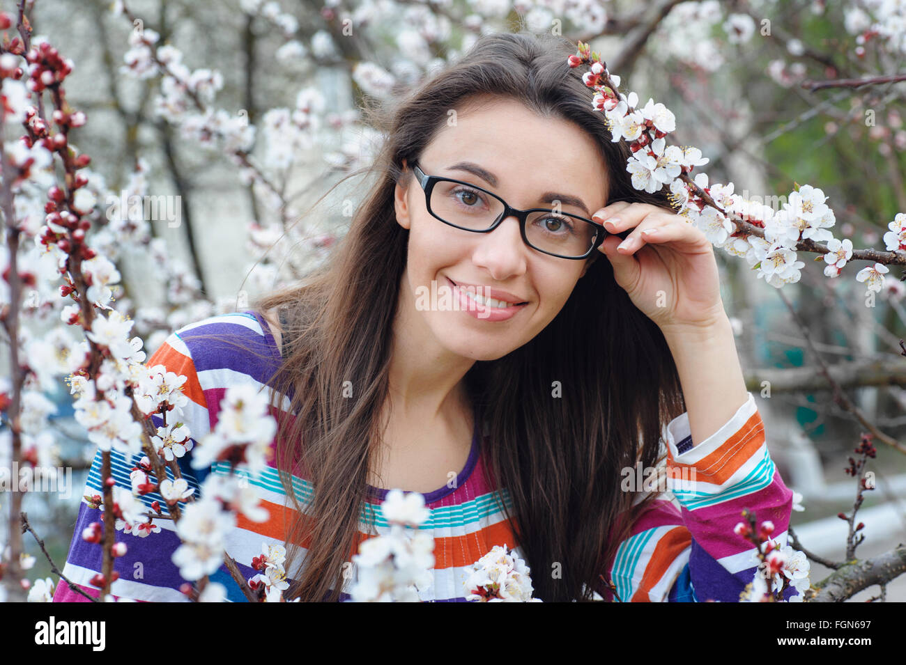 Porträt von lächelnden kaukasischen Brünette Frau in Blüte Frühlingsgarten Stockfoto