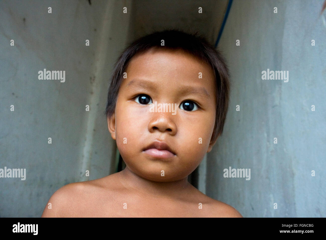 Ein kleiner Junge, der in Armut lebenden Menschen sieht außerhalb seiner Heimat Holz in einem Slum in Kampong Cham, Kambodscha. Stockfoto