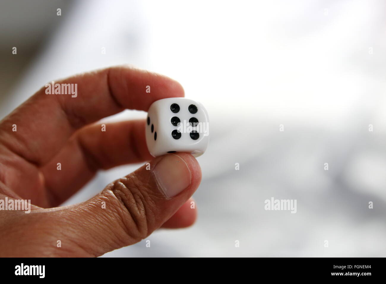 Linke Hand hält einen Würfel Stockfoto