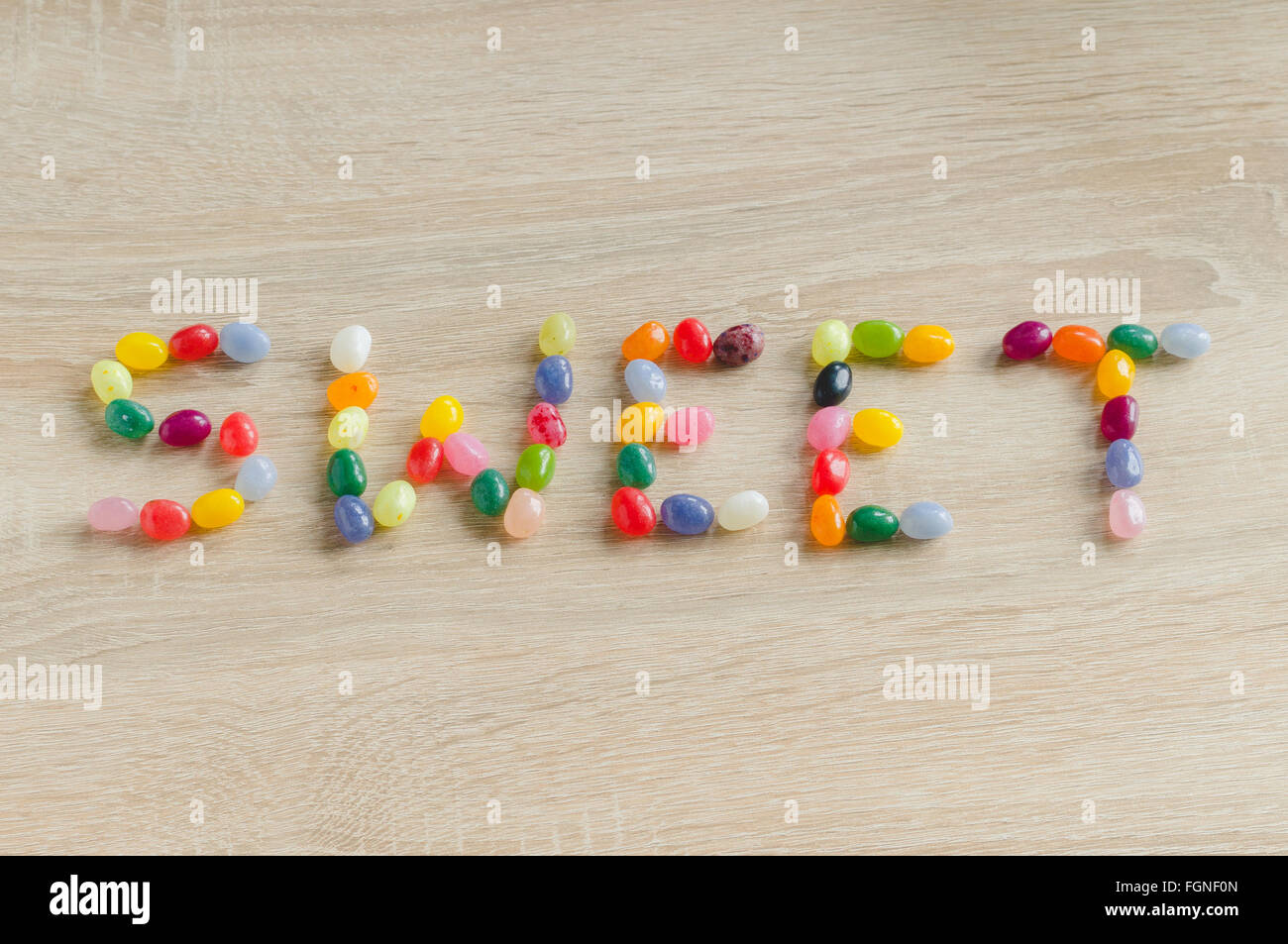 Wort-süßes aus Gummibärchen auf hölzernen Hintergrund Stockfoto
