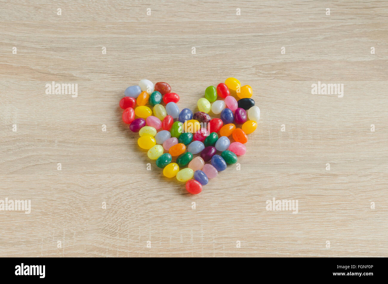 Herzsymbol von Gummibärchen auf hölzernen Hintergrund Stockfoto