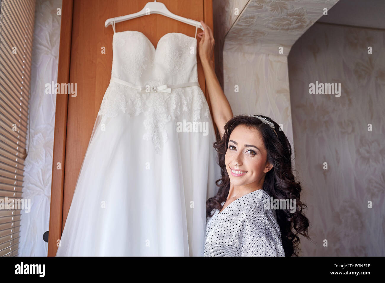 Schöne Braut am Morgen der Hochzeit mit ihrem Kleid versucht Stockfoto