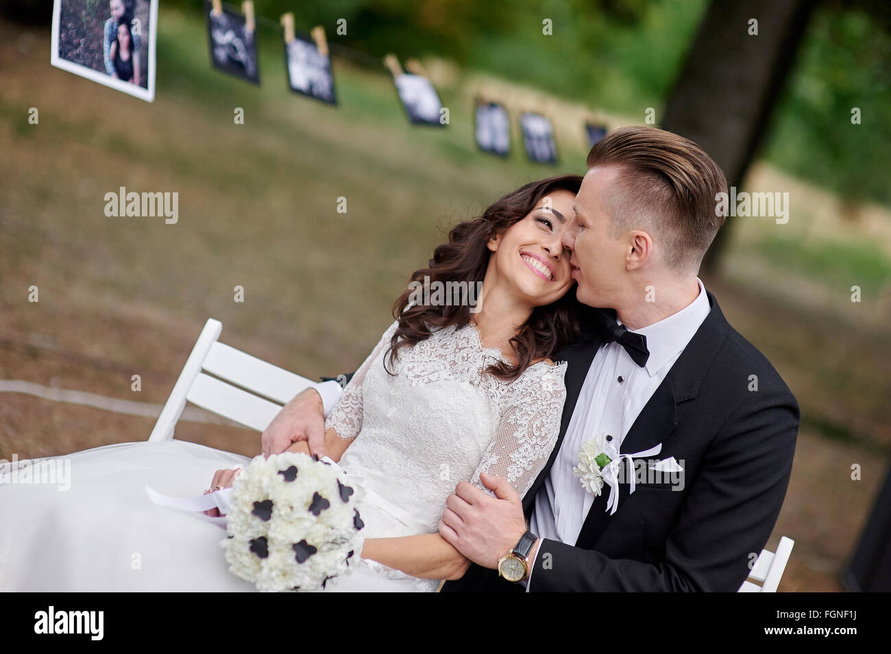Glückliche Braut und Bräutigam sitzen auf der Bank im park Stockfoto