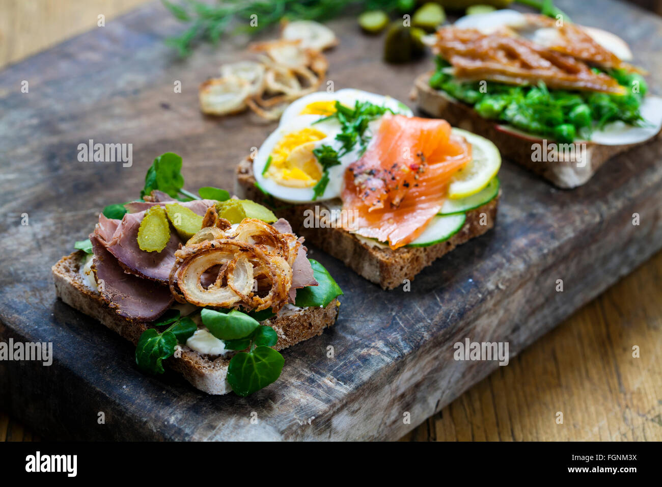 Skandinavische belegte Brötchen mit geräucherter Makrele, Lachs und Ei und Roastbeef und knusprigen Zwiebeln Stockfoto