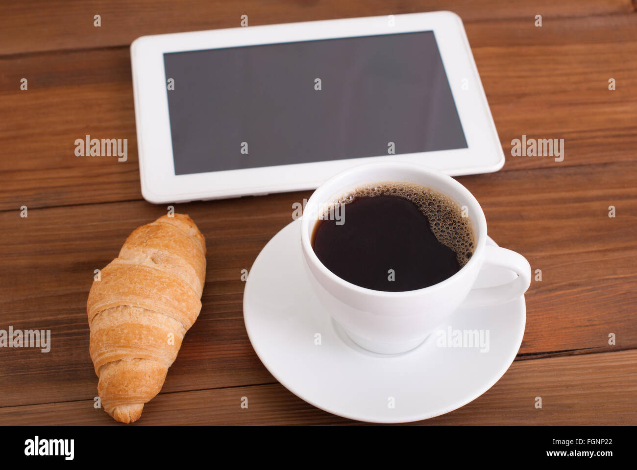 Tasse Kaffee und ein Croissant-digital-Tablette auf dem Tisch. Stockfoto