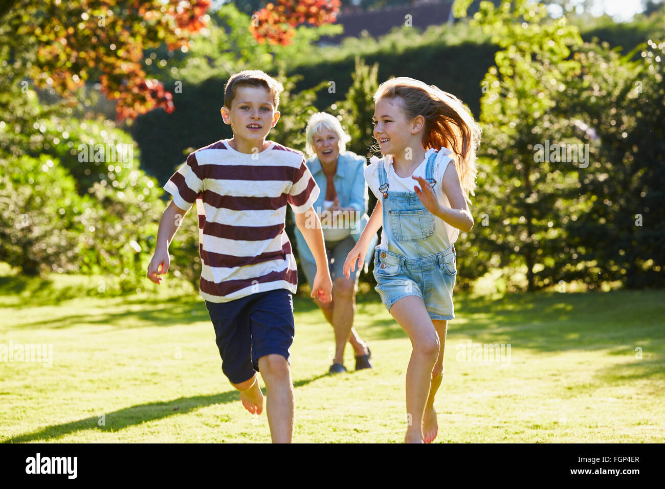 Bruder und Schwester im sonnigen Garten laufen Stockfoto
