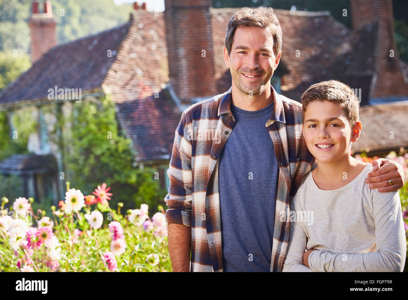 Porträt, Lächeln, Vater und Sohn im sonnigen Blumengarten Stockfoto