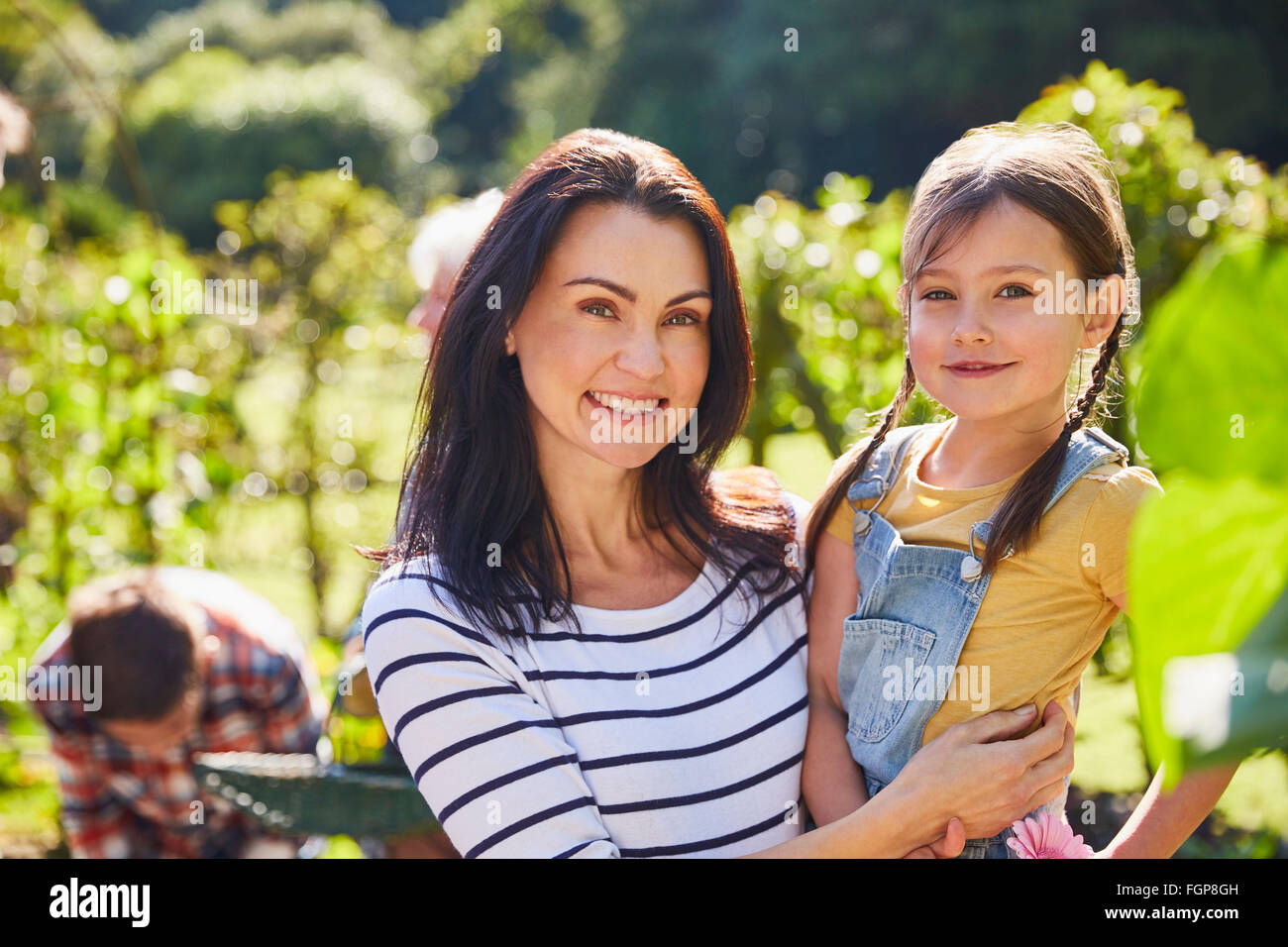 Porträt, Lächeln, Mutter und Tochter umarmt im sonnigen Garten Stockfoto