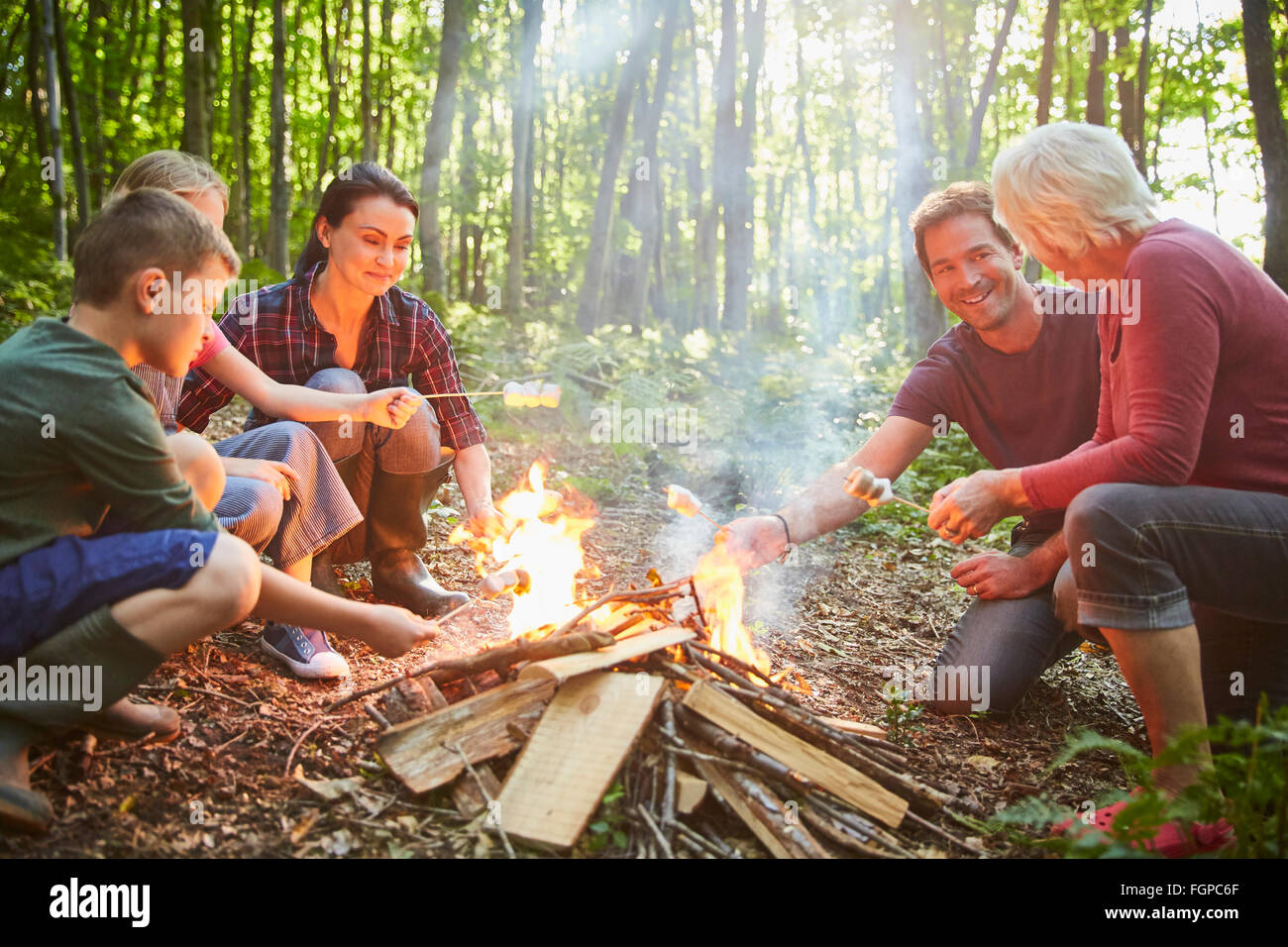 Mehr-Generationen-Familie Rösten Marshmallows am Lagerfeuer im Wald Stockfoto