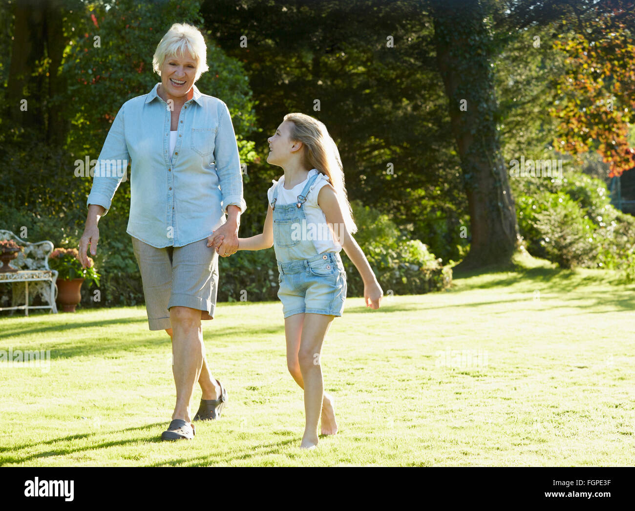 Großmutter und Enkelin Hand in Hand und Wandern im sonnigen Garten Stockfoto