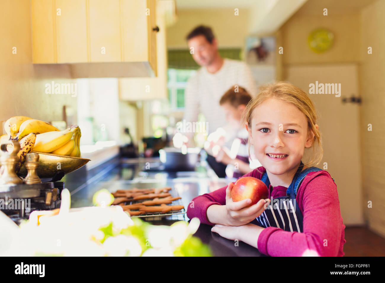 Porträt lächelndes Mädchen essen Apfel in Küche Stockfoto