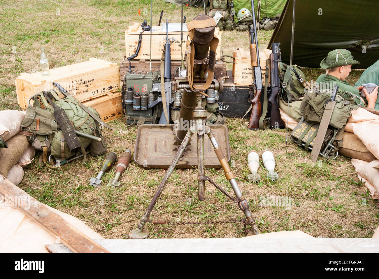 Vietnam Krieg Re-enactment. American heavy Mörtel in sandbagged Position mit verschiedenen Geräten an der Rückseite gegen Kisten gestapelt. Einige Soldaten entspannend. Stockfoto