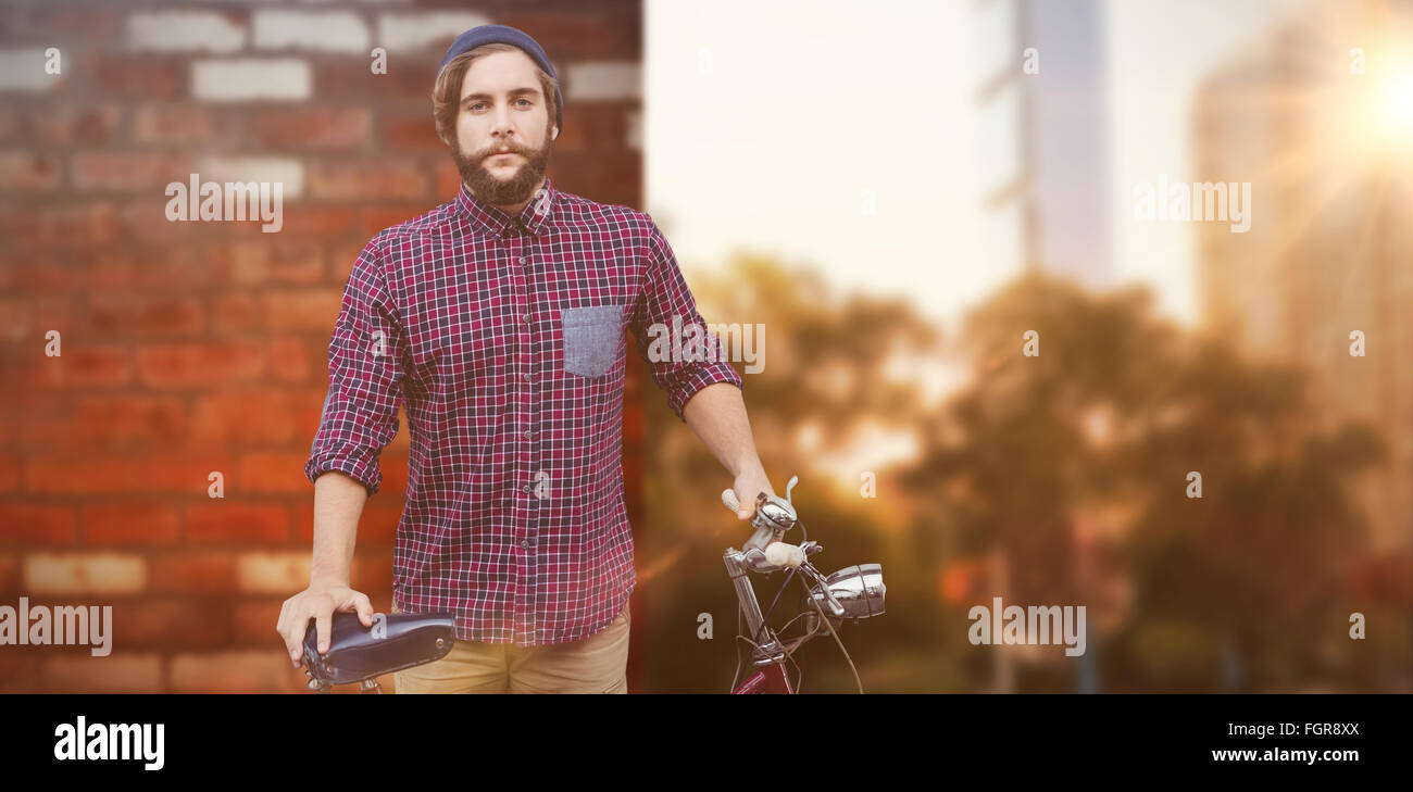 Zusammengesetztes Bild Hipster mit Fahrrad gegen Zaun Stockfoto
