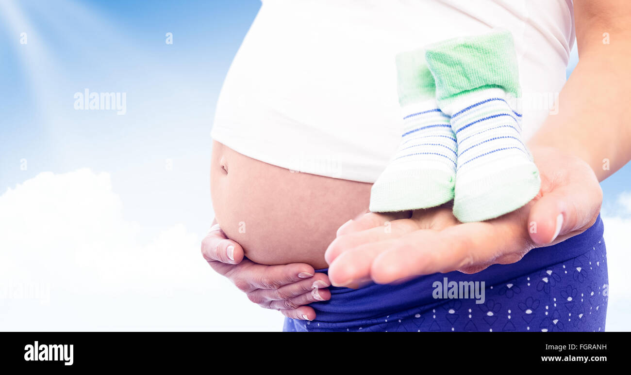 Zusammengesetztes Bild schwangere Frau mit Baby-Schuhe Stockfoto