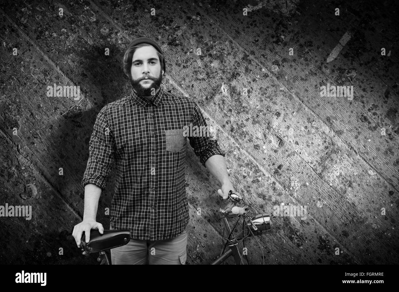 Zusammengesetztes Bild Hipster mit Fahrrad gegen Zaun Stockfoto